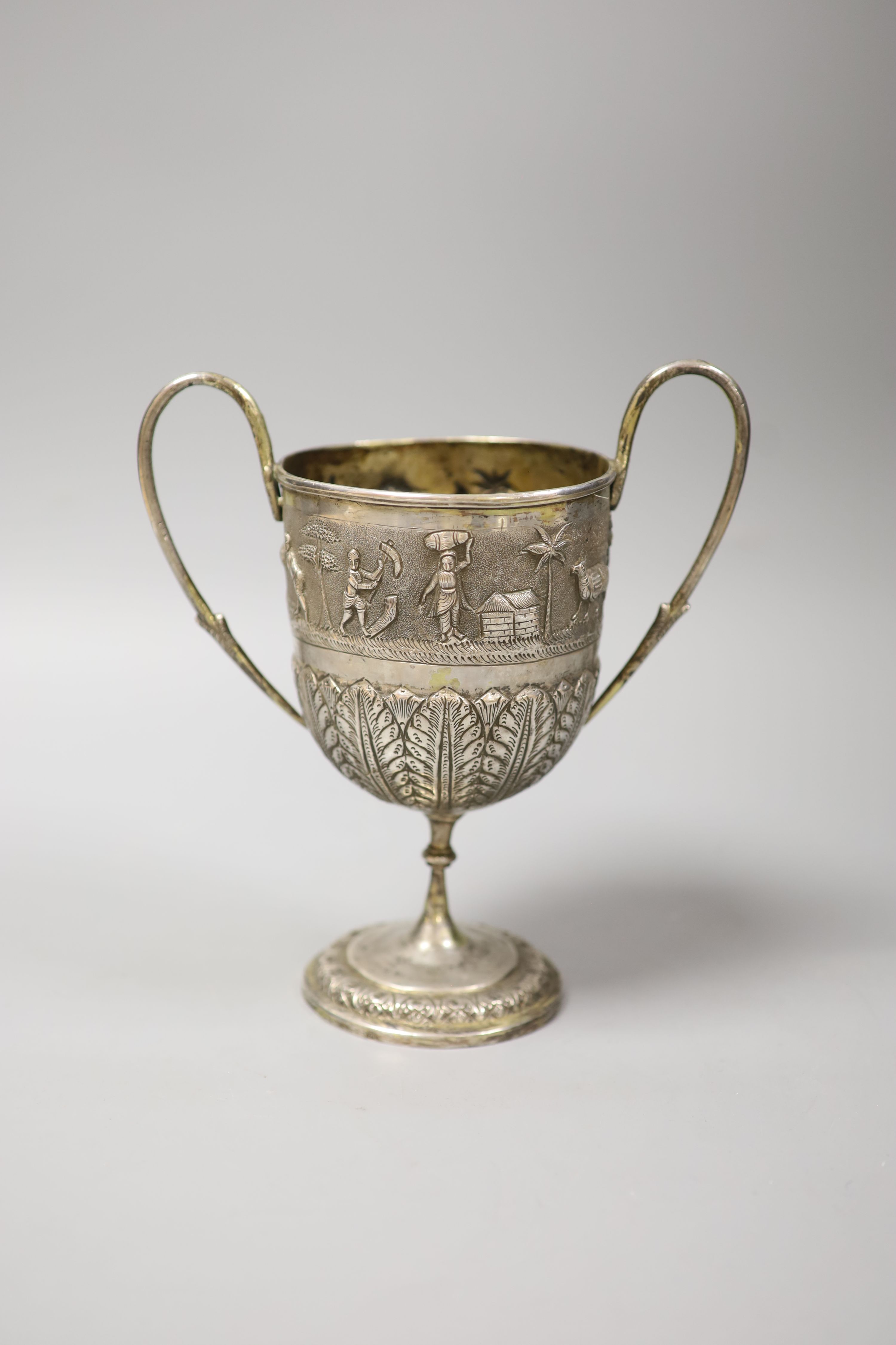 An embossed Indian white metal two handled pedestal trophy cup, height 22.2cm, 12.5oz.